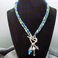 Beaded necklace with a heart toggle closure featuring charms on a black mannequin against a neutral background