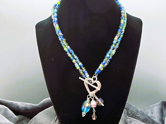 Beaded necklace with a heart toggle closure featuring charms on a black mannequin against a neutral background